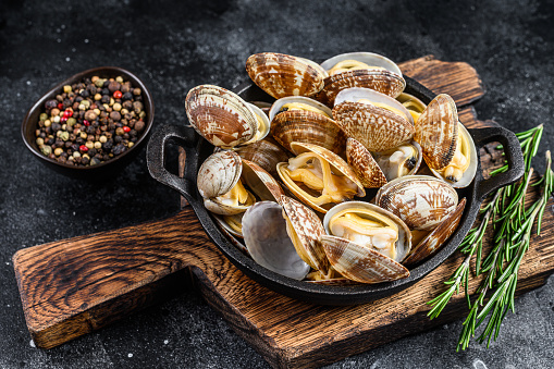 Cooked Clams vongole in a pan. Black background. Top view.