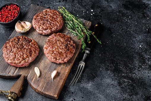 Barbacoa empanadas de carne de res a la parrilla para hamburguesa de carne picada y hierbas en una tabla de madera. Fondo negro. Vista superior. Copiar espacio photo