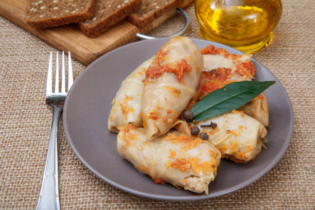 istock Delicious homemade cabbage rolls stuffed with rice and meat on dish with fork and bottle of sunflower oil. 1295775032