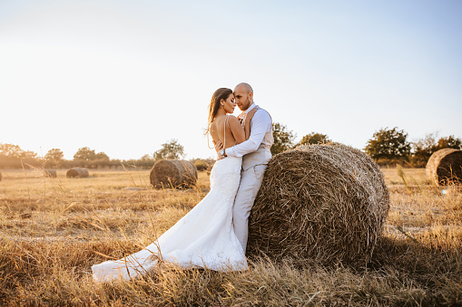 Wedding young couple hugging  in a hay field on sunny autumn day