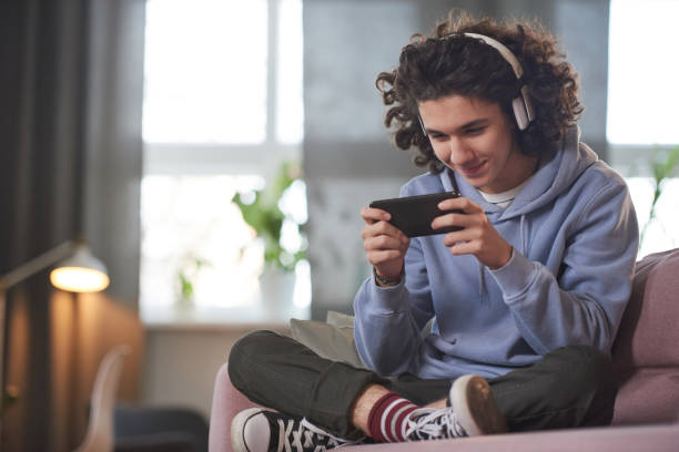 teenage junge spielen auf dem handy - portable player stock-fotos und bilder