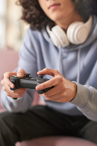 Close-up of guy in headphones holding joystick playing computer video games in the room