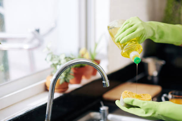 femme versant le savon de plat sur l’éponge - liquide vaisselle photos et images de collection