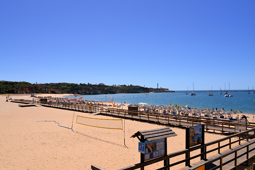 Algarve / Faro District, Portugal: Praia Grande beach, located on the estuary of the Arade river - boardwalk and horizon over the harbour entrance.