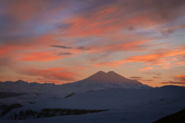 Mount Elbrus covered with snow in winter and colorful evening sky Mount Elbrus covered with snow in winter and colorful evening sky north caucasus photos stock pictures, royalty-free photos & images