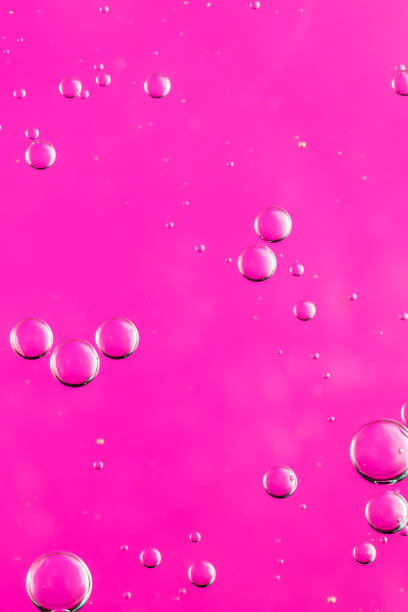 istock oil drops on water on a pink background 1295783200