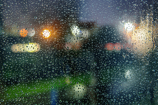 A background of rain drops at night in a window, with a defocused city in the background