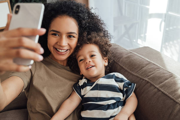la joven madre y su pequeño hijo pasan tiempo juntos. un chico feliz tomando un selfie con su madre. - madre fotos fotografías e imágenes de stock