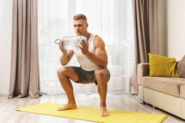 istock Young athletic man using big bottle of water for home workout 1295784639
