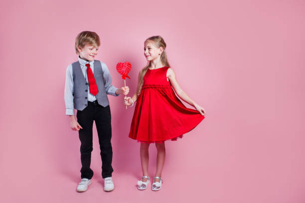 conceito de dia dos namorados. garotinho e menina com pirulito vermelho doce em forma de coração. crianças bonitas comem doces. - child valentines day candy eating - fotografias e filmes do acervo