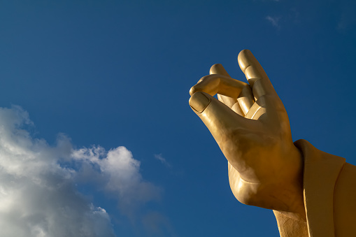 The hand of a huge gold Buddha statue located in a famous temple in Busan, South Korea, was photographed in the blue sky.