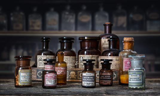 Bottles with drugs from old medical, chemical and pharmaceutical glass. Chemistry and pharmacy history concept background. Retro style. Chemical substances-sulfamerazin, arsenic trioxid, quinine sulphate, iron and strychnine, santonin and calomel.