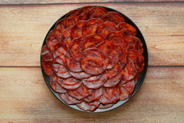 porción de chorizo ibérico de bellota sobre plato negro sobre vista rústica de mesa de madera - península ibérica fotografías e imágenes de stock