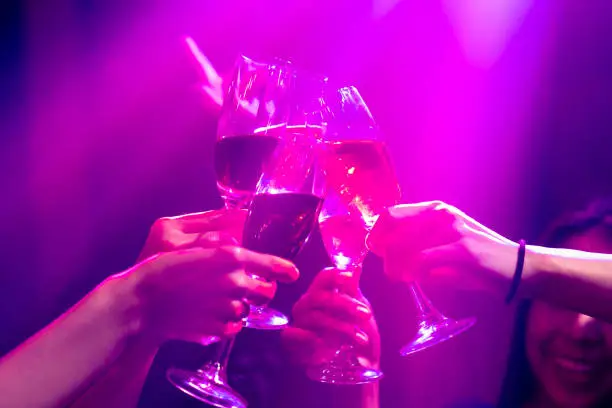 Photo of Group of people toast drinks at party in dancing club