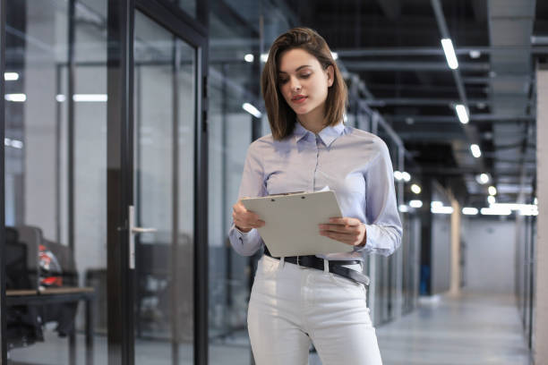 istock Businesswoman walking along the office corridor with documents. 1295792443