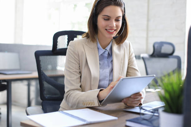 istock Cheerful female manager sitting at office desk, performing corporate tasks using wireless connection on digital gadgets. 1295793459
