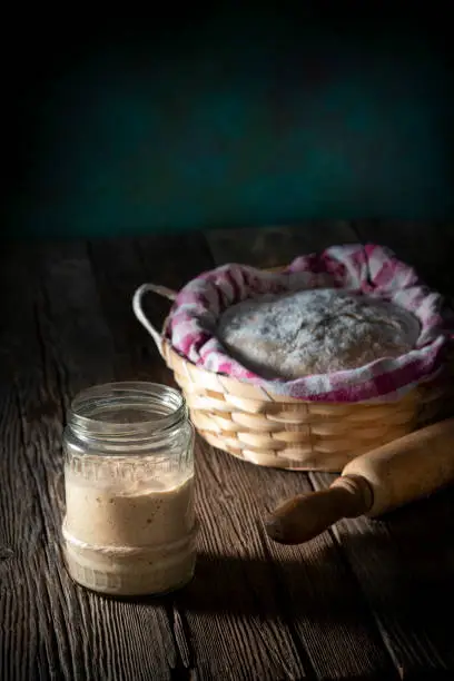 Sourdough glass preparing real bread dough homemade bakery in moody wooden table low key dark background