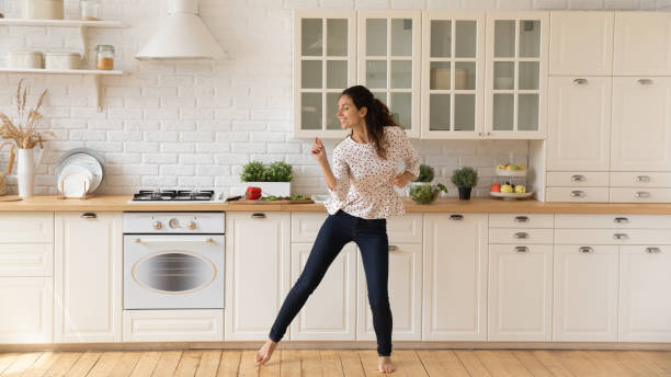 istock Happy female renter enjoy dancing in home kitchen 1295795440