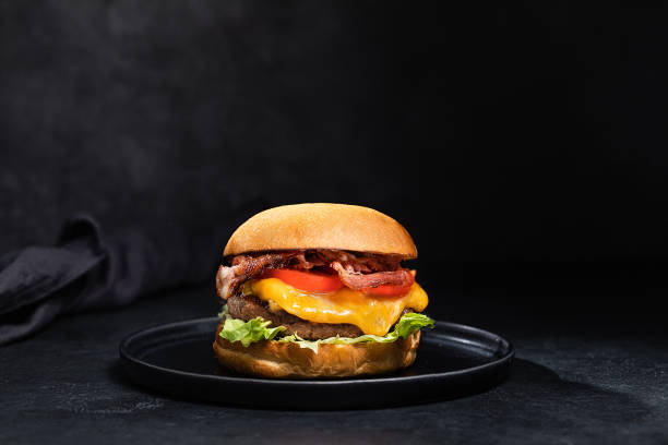 hamburguesa de queso con tocino sobre fondo negro oscuro - salsa de tomate fotos fotografías e imágenes de stock