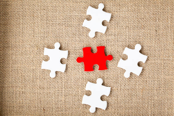 Three white puzzle pieces are connected on a blue background, with a fourth piece about to be added. The image symbolizes the process of integration, collaboration, and finding solutions