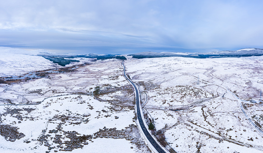 The view from a drone of a narrow rural road in a remote location in rural Dumfries and Galloway south west Scotland after a prolonged period of cold weather snow can be seen lying on the ground\nThe panorama was created by merging several images together