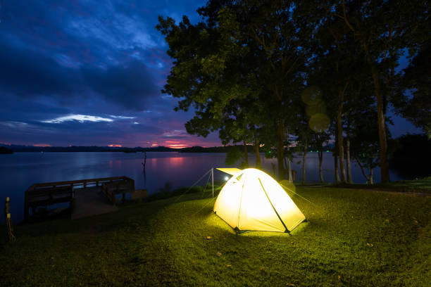 istock Camping tent on green grass field under cloudy sky at night time 1295799707