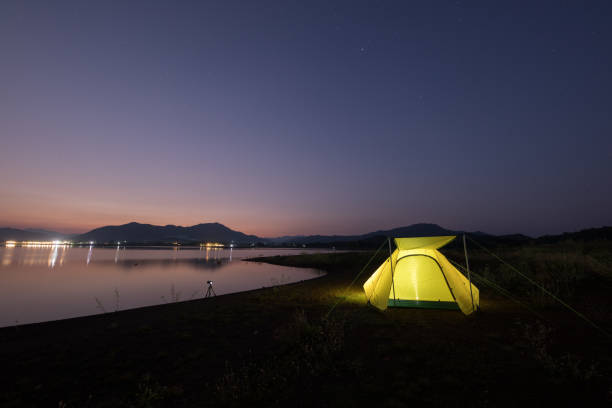 istock Camping tent on green grass field under cloudy sky at night time 1295799902