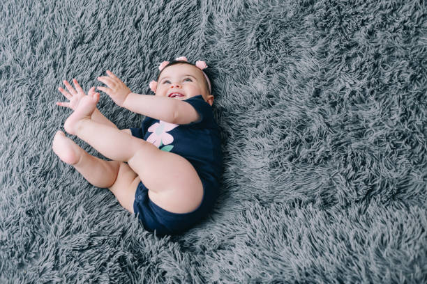 istock Cheerful seven months old baby laughing and playing on her bed 1295800155