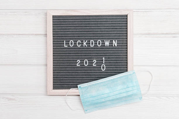 istock Flatlay letter board with message text lockdown 2021. White protective gloves, medical masck for face. 1295800218