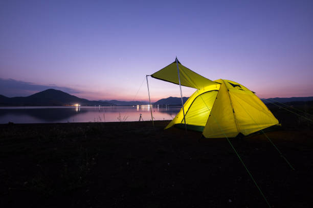 istock Camping tent on green grass field under cloudy sky at night time 1295800229