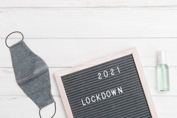 istock Flatlay letter board with message text lockdown 2021. White protective gloves, medical masck for face. 1295800260