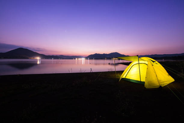 istock Camping tent on green grass field under cloudy sky at night time 1295800302