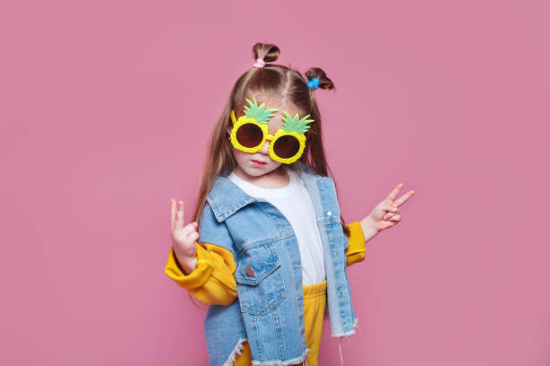 夏のファッションコンセプト。ピンクの背景に大きなパイナップルサングラスで陽気な小さな女の子 - fashion model small one person happiness ストックフォトと画像