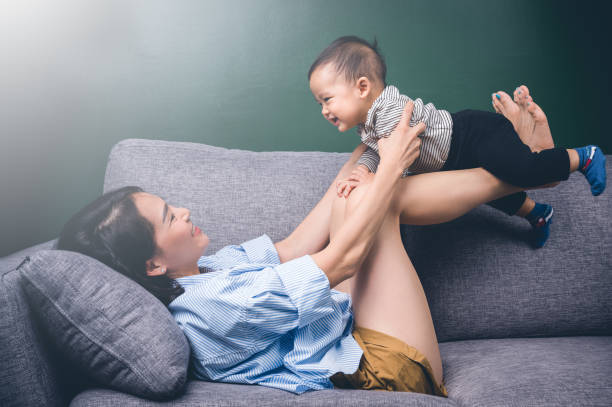 Happy young mother play with her son or child on sofa.Family concept. stock photo