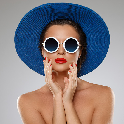 Young and beautiful woman wearing blue hat and sunglasses is ready for vacation