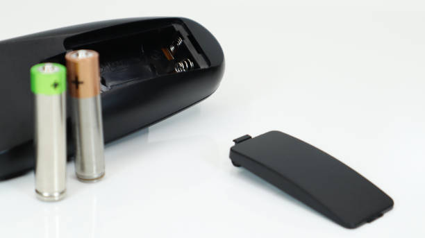 istock Black TV remote control with AAA alkaline batteries on a white background. Battery replacement, spare parts. Close up of an empty battery compartment of the remote control 1295811041