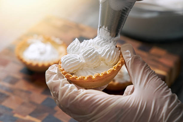 istock Closeup of a pastry chef decorating a cream dessert 1295811046