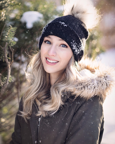 A young blonde woman with wavy hair, dressed in warm clothes under the falling snow