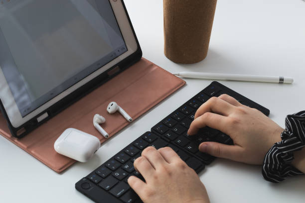 female person typing on a black bluetooth keyboard, working home office at a tablet computer - typewriter key audio imagens e fotografias de stock