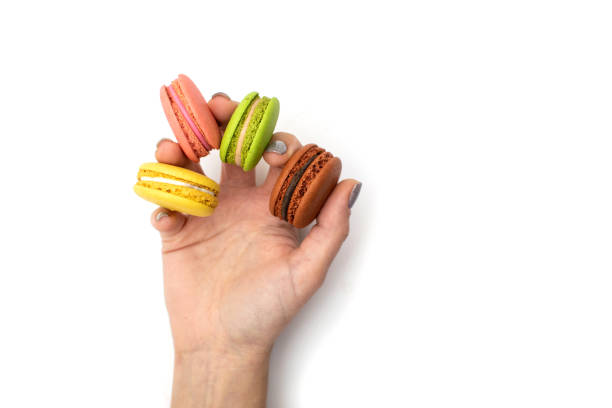 istock Macaroni cakes in a female hand on a white plate. Isolated. 1295811343