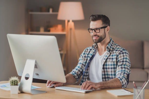istock Photo of young cheerful handsome man happy positive smile remote work computer programmer desk indoors 1295811488
