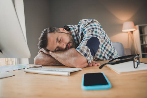 istock Photo of young handsome exhausted tired man sleep at workplace break pause stressed overworked rest relax indoors 1295812113
