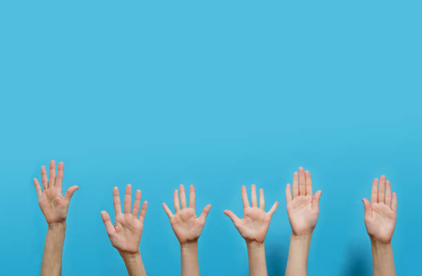 istock many Hands with open palms raised up on a blue background. studio shot and copy space 1295812193