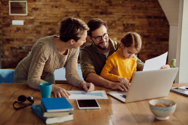 istock Happy working father using laptop with his family at home. 1295812300