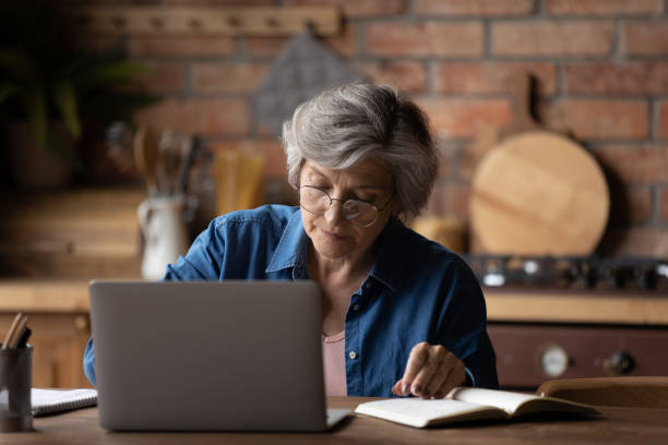 istock Focused middle aged woman in eyeglasses working remotely on computer. 1295813920