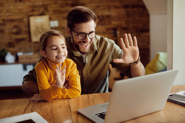 istock Happy father and daughter waving while having video call at home. 1295815069