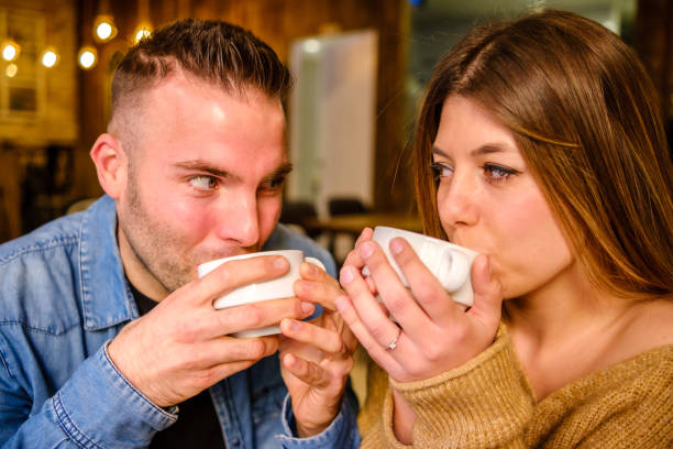 istock Couple looks at each other while drinking coffee in a coffee shop 1295816569