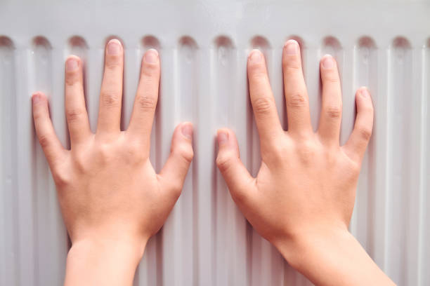 istock Girl warms her hands on the radiator 1295817833