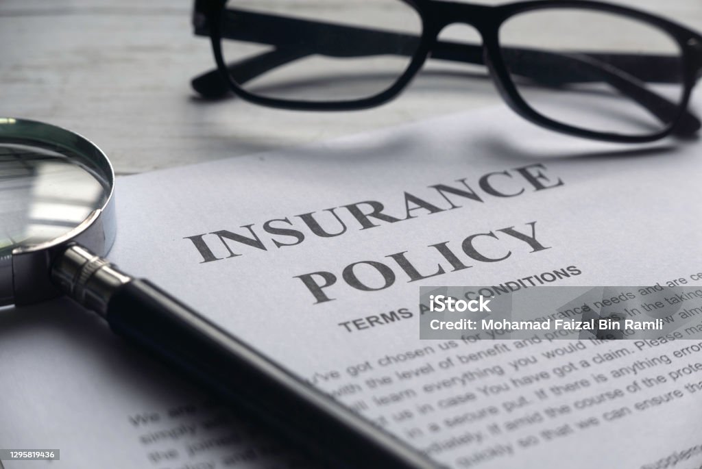 Selective focus of magnifying glass,glasses and Insurance Policy letter on a white wooden background. Insurance Stock Photo