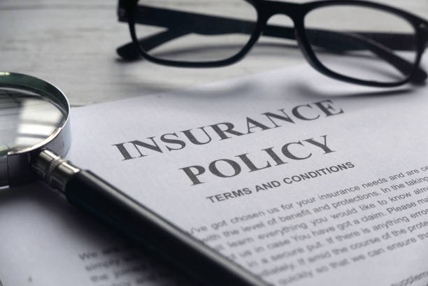 Selective focus of magnifying glass,glasses and Insurance Policy letter on a white wooden background. stock photo
